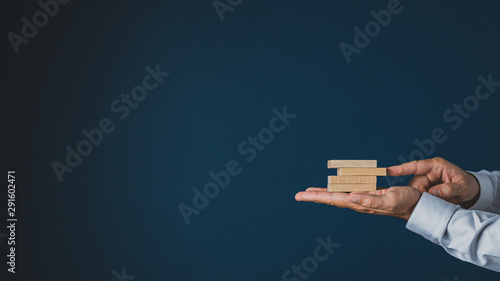 Businessman stacking wooden pegs