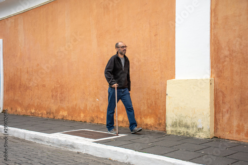 Man with a disabled leg walks with a cane © Rogerio
