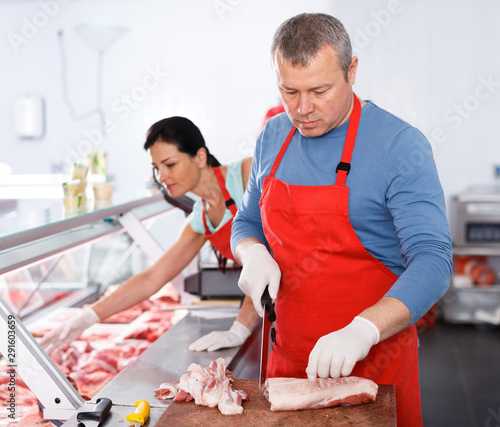 Man and woman seller working in butcher’s shop