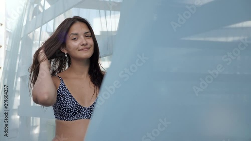 Snazzy girl in bikini standing and smartening up at a see-through veil in slo-mo photo