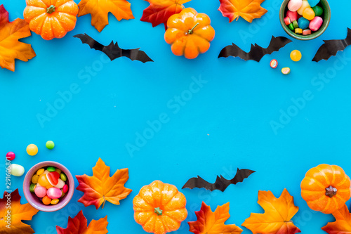 Bright Halloween composition with sweets, bats and pumpkins on blue background top view frame space for text