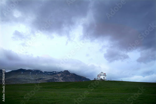 Rain Clouds Rolls Towards A White Farmhouse On A Hill In Iceland