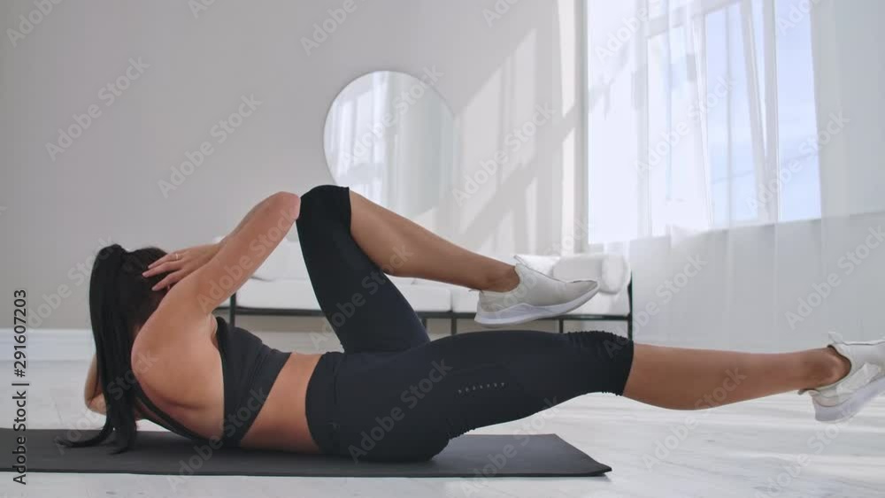 Young girl doing bicycle crunches exercise, working out at home. Young fitness girl doing easy intensive bicycle crunches exercise at home lying on floor, sporty. Young girl doing bicycle crunches exercise, working out at home. Young fitness girl doing easy intensive bicycle crunches exercise at home lying on floor, sporty.
