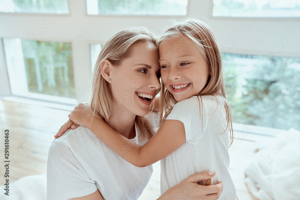 I love my mom. Happy Mothers Day. Beautiful mom with her little cute daughter are having fun at home. Hugging and kissing each other and smiling. I love my mom. Happy Mothers Day. Beautiful mom with her little cute daughter are having fun at home. Hugging and kissing each other and smiling.