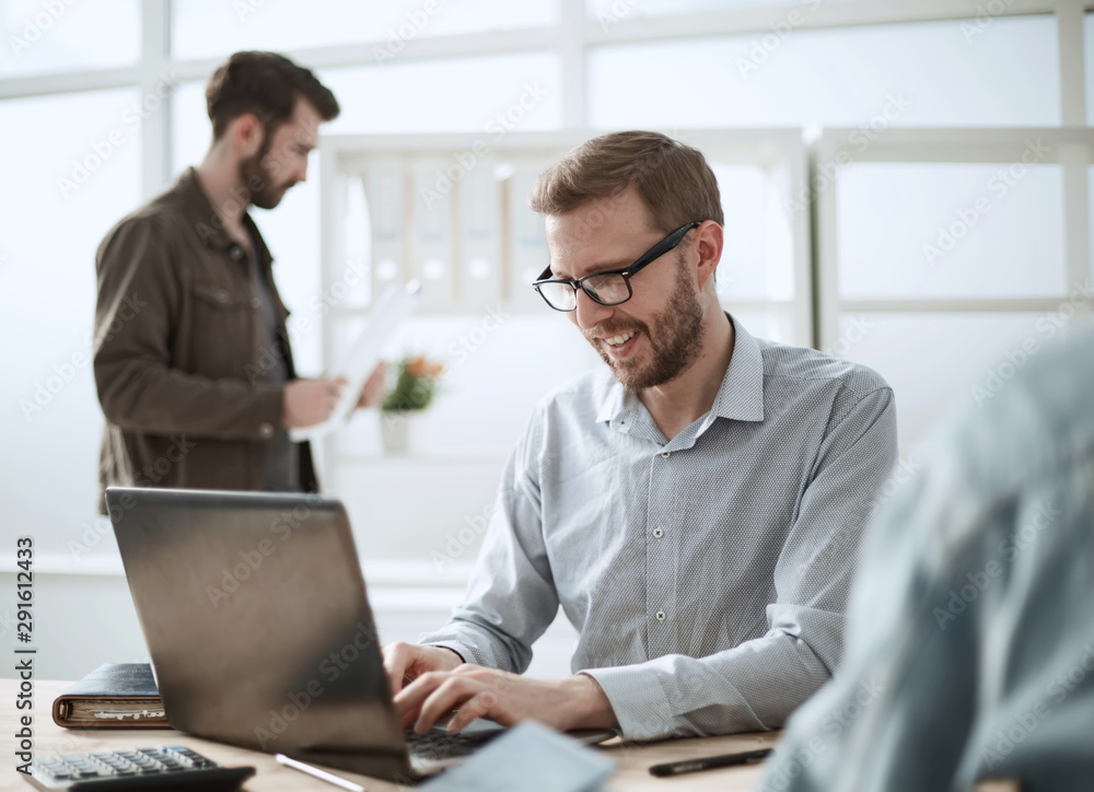 smiling businessman uses a laptop to work on a new project smiling businessman uses a laptop to work on a new project