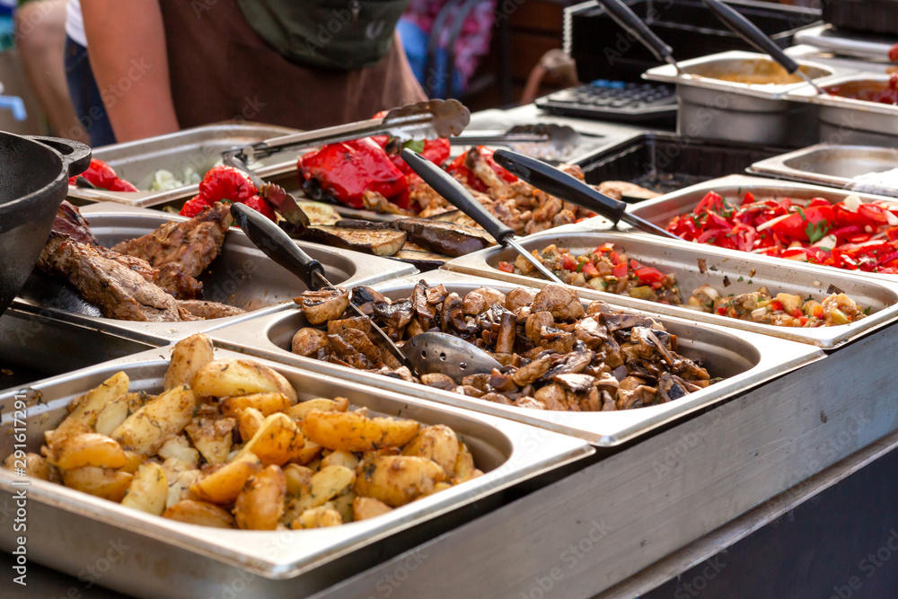 Obraz premium A counter with metal trays containing grilled food. Food and cooking equipment at a street food festival