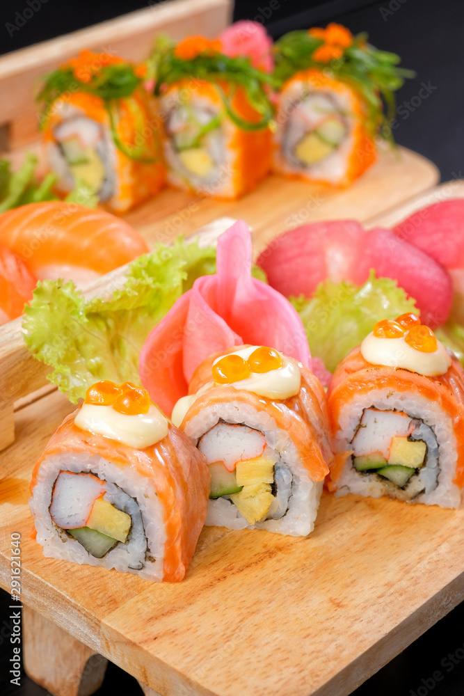Japanese Cuisine - Sushi Roll on wood plate in black background Japanese Cuisine - Sushi Roll on wood plate in black background