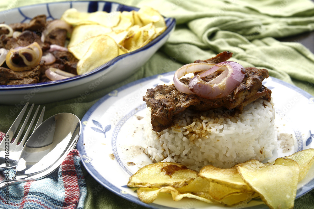 Bistek Tagalog or fried pork tenderloin in soy sauce with potato chips