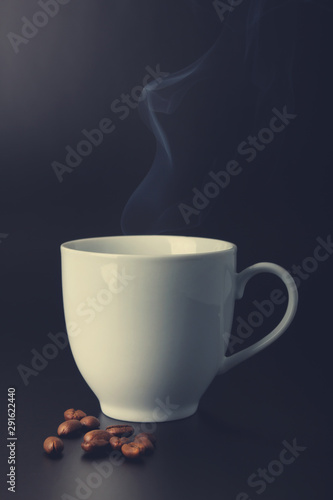 white cup with hot liquid and steam on black