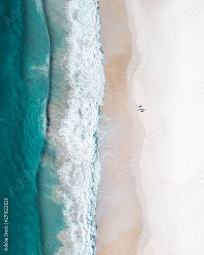 Tablou canvas Aerial of a beach at sunrise with people walking on the sand, enjoying the sun in small coves during a summer holiday morning
