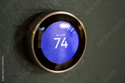 Isolated smart home thermostat on blue wall up close macro in cooling room
