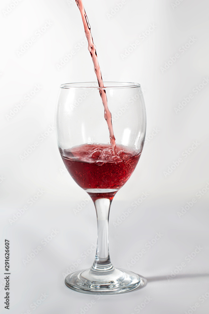 Pouring red wine on a wine glass. frozen movement while splashing with the cup shadow on the right side. Pouring red wine on a wine glass. frozen movement while splashing with the cup shadow on the right side.