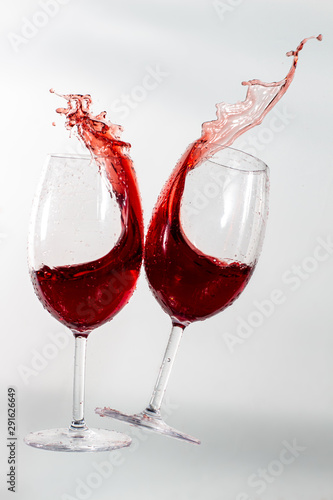 Wine glasses splashing with each other with red merlot wine