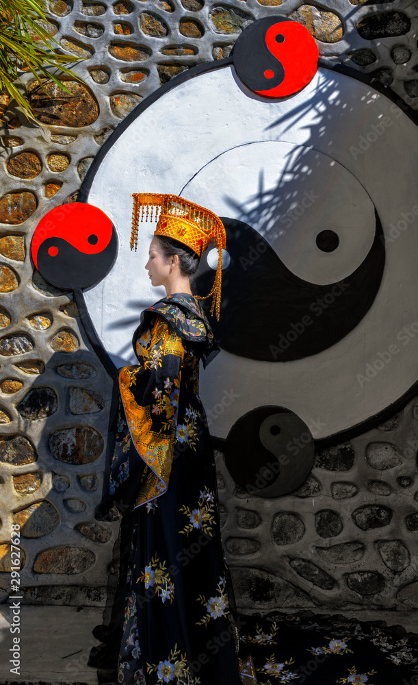 Chinese woman wearing native traditional dress standing on ying yang sign wall in Chinese village in Thailand Chinese woman wearing native traditional dress standing on ying yang sign wall in Chinese village in Thailand