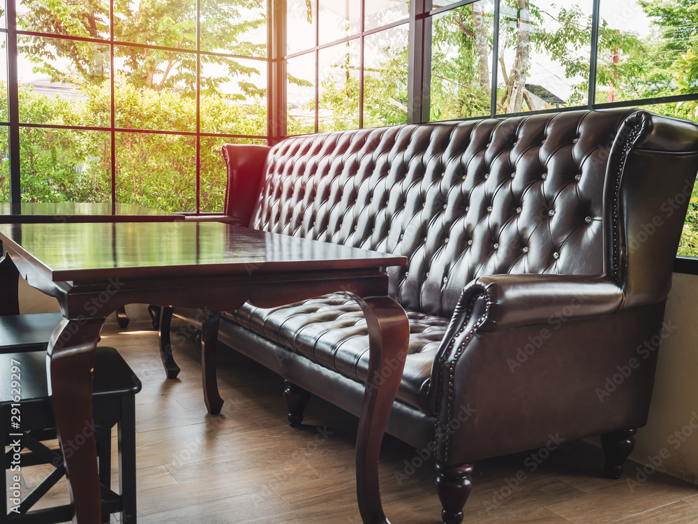 Vintage brown leather sofa and wooden table decoration in cafe.