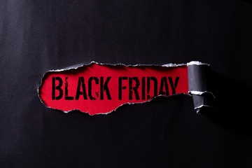 Top view of Black torn paper and the text black friday on a red background. Black Friday composition.