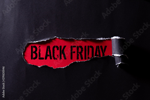 Top view of Black torn paper and the text black friday on a red background. Black Friday composition. photo