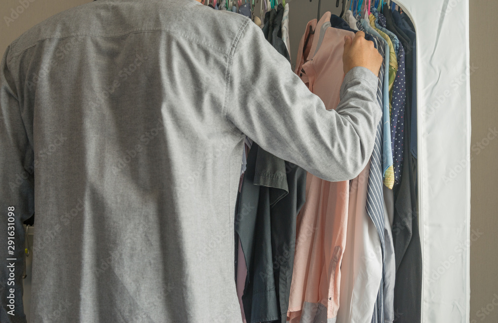 Man select their shirt in clothes closet