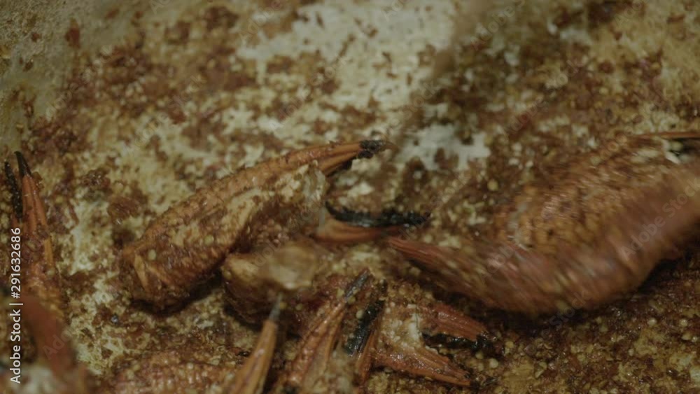 A slow-motion, extreme closeup shot of preparing a Vietnamese-style salted crab claw dish (Cua Rang Muoi) inside a steel pan and mixing it with spices using a flat metal ladle. A slow-motion, extreme closeup shot of preparing a Vietnamese-style salted crab claw dish (Cua Rang Muoi) inside a steel pan and mixing it with spices using a flat metal ladle.