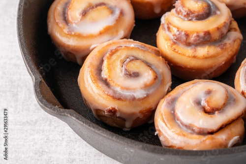 Homemade baked cinnamon rolls baked in an iron skillet with icing