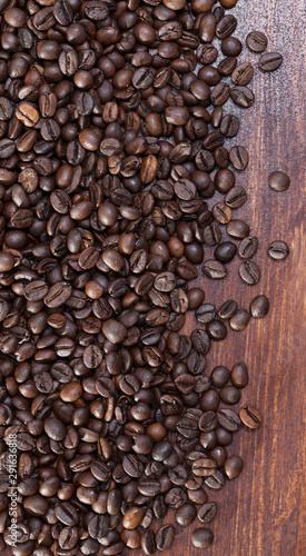 Dark coffee beans on natural wooden background, no people