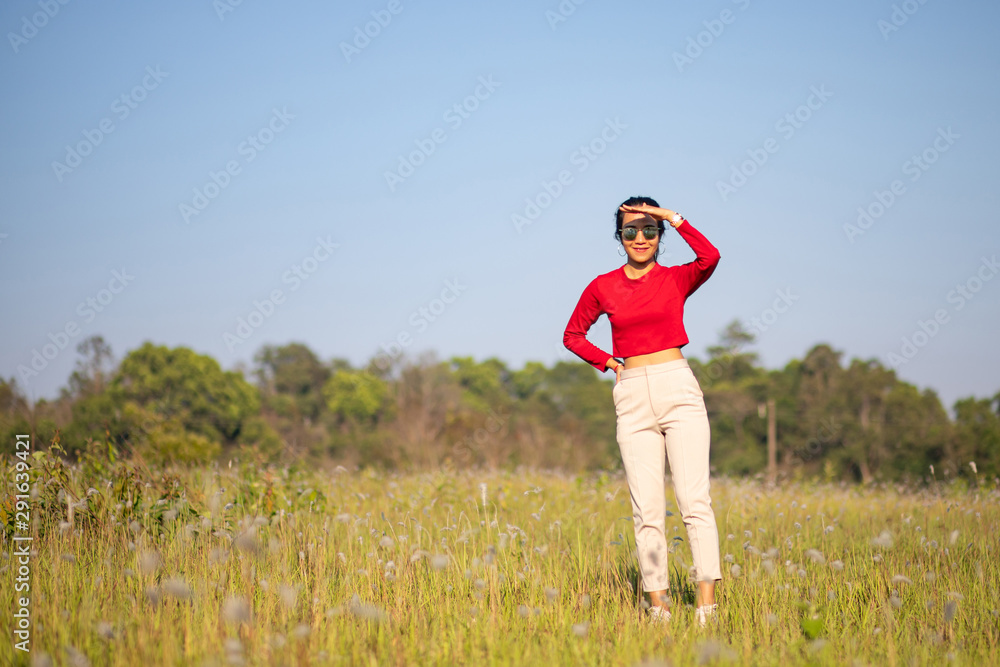 Hipster Asian woman in red and sunglasses on white flower and grass field Hipster Asian woman in red and sunglasses on white flower and grass field