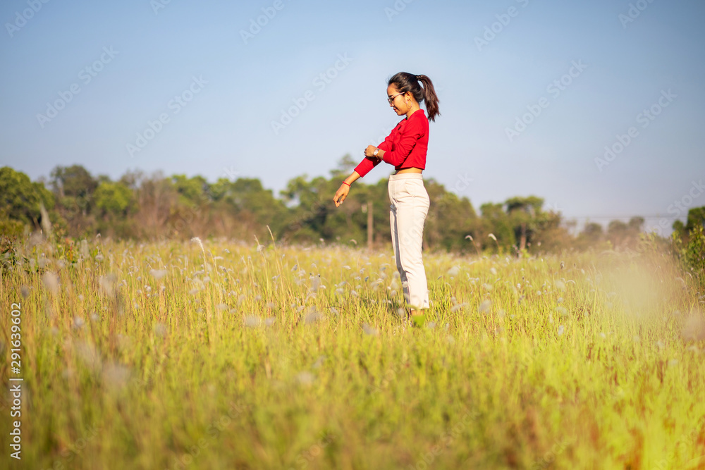 Hipster Asian woman in red and sunglasses on white flower and grass field Hipster Asian woman in red and sunglasses on white flower and grass field