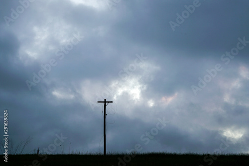 Cross silhouette in a field on a dark cloudy day