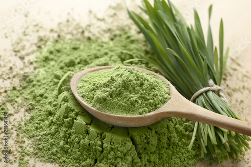 фотографія Wooden spoon with wheat grass powder and green sprouts on table
