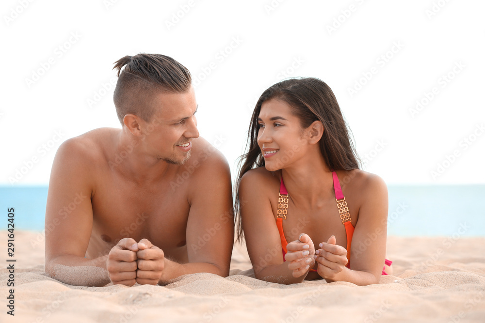 Young woman in bikini spending time with her boyfriend on beach. Lovely couple