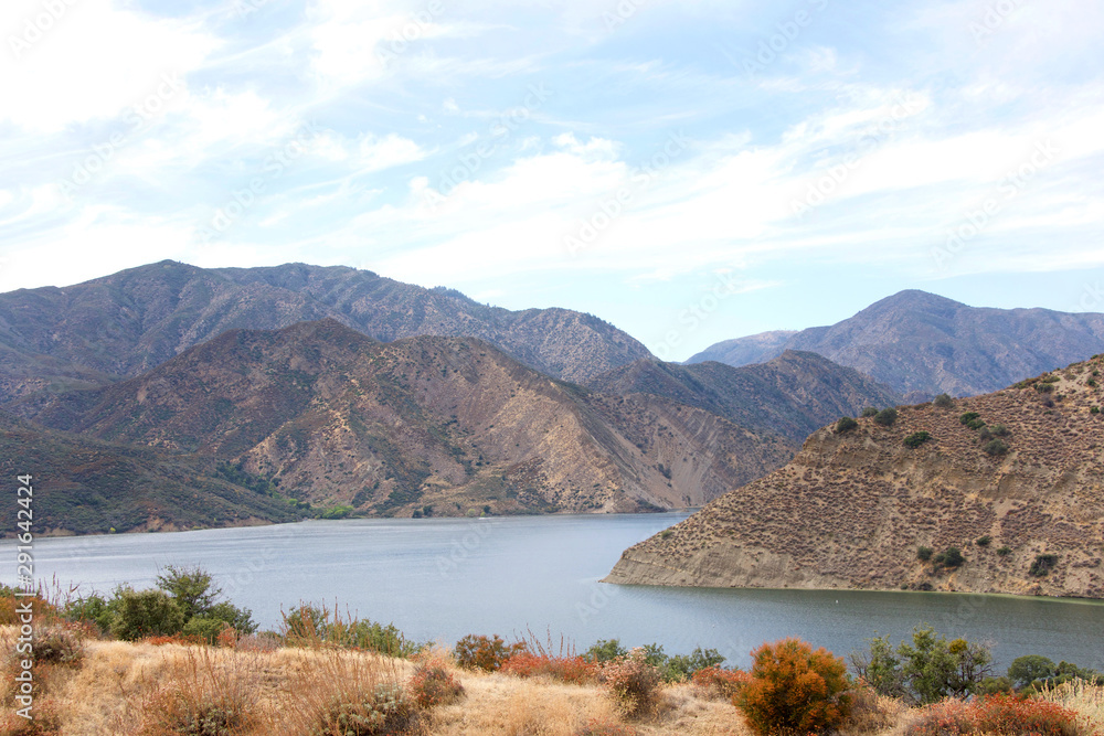 View of half of Pyramid Lake with cloudy blue sky background. Pyramid Lake offers boating, fishing, jet skiing, and picnic areas, including five unique sites that are accessible only by boat