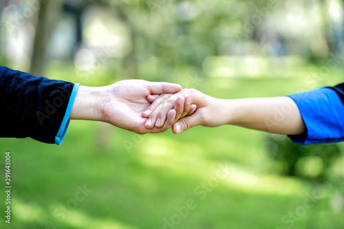 Couple hold hands in green field. Hand in hand, hand giving a helping hand.. © somchairakin