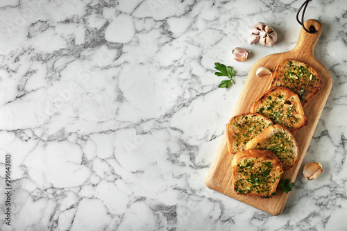 Fototapeta Naklejka Na Ścianę i Meble -  Slices of toasted bread with garlic and herbs on marble table, flat lay. Space for text