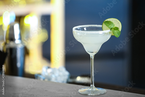 Fresh alcoholic cocktail with lime and mint on bar counter, space for text photo