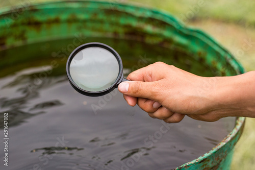 A hand holds a magnifier and looks at water. The concept of research water for pollution, protecting the environment. Close-up shot of hands and magnifier. Image. photo