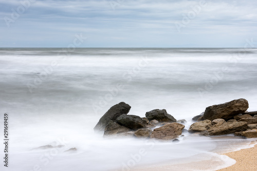 Storm in the sea, big foamy waves crash on rocks