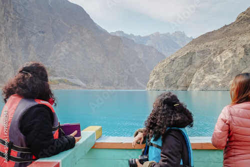 Asian women tourists enjoy beautiful landscape scenery of turquoise blue water of Attabad lake against Karakoram mountain range.Hunza Valley.Gilgit Baltistan, Pakistan. Selective focus on background. © Sulo Letta