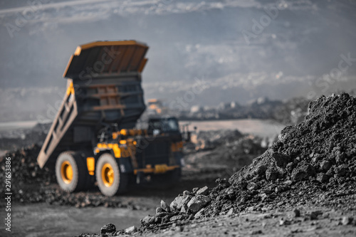 Close-up coal anthracite storage, in background large mining dump truck unloads ore