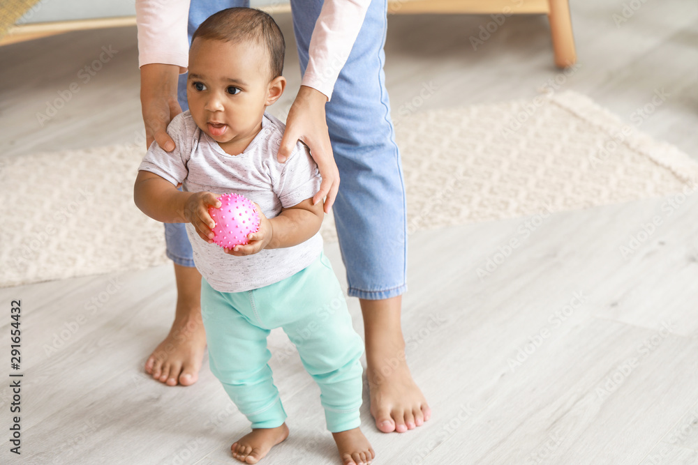 African-American mother teaching her little baby to walk at home African-American mother teaching her little baby to walk at home