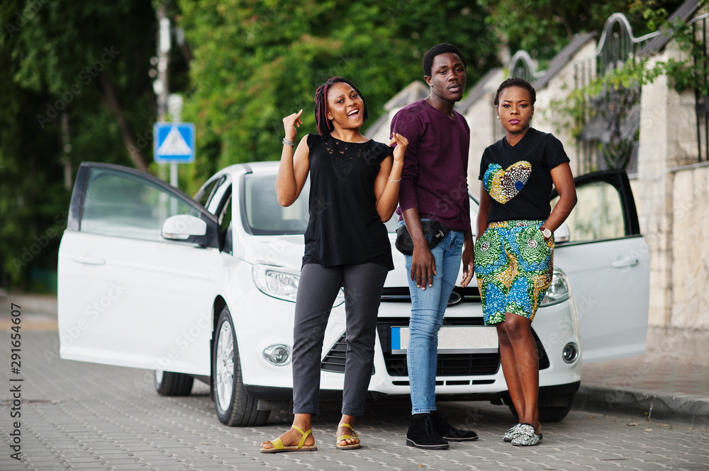 Three african american friends stay near car.