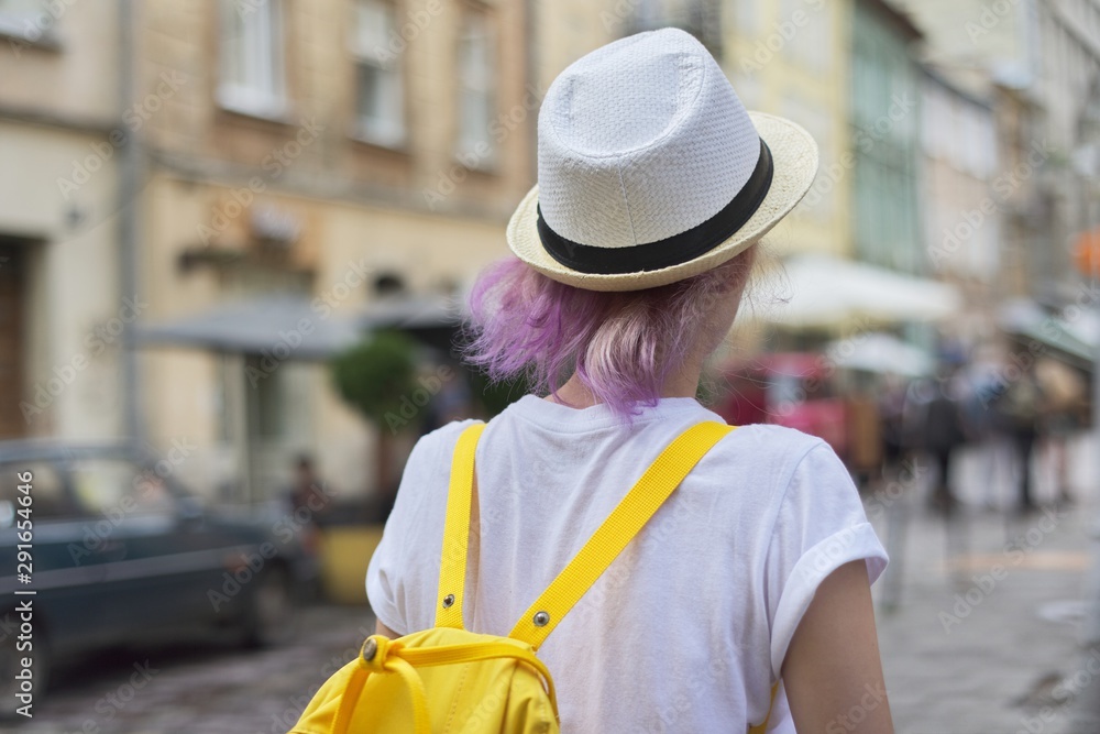 Portrait of girl in hat with trendy purple lilac hair, back view