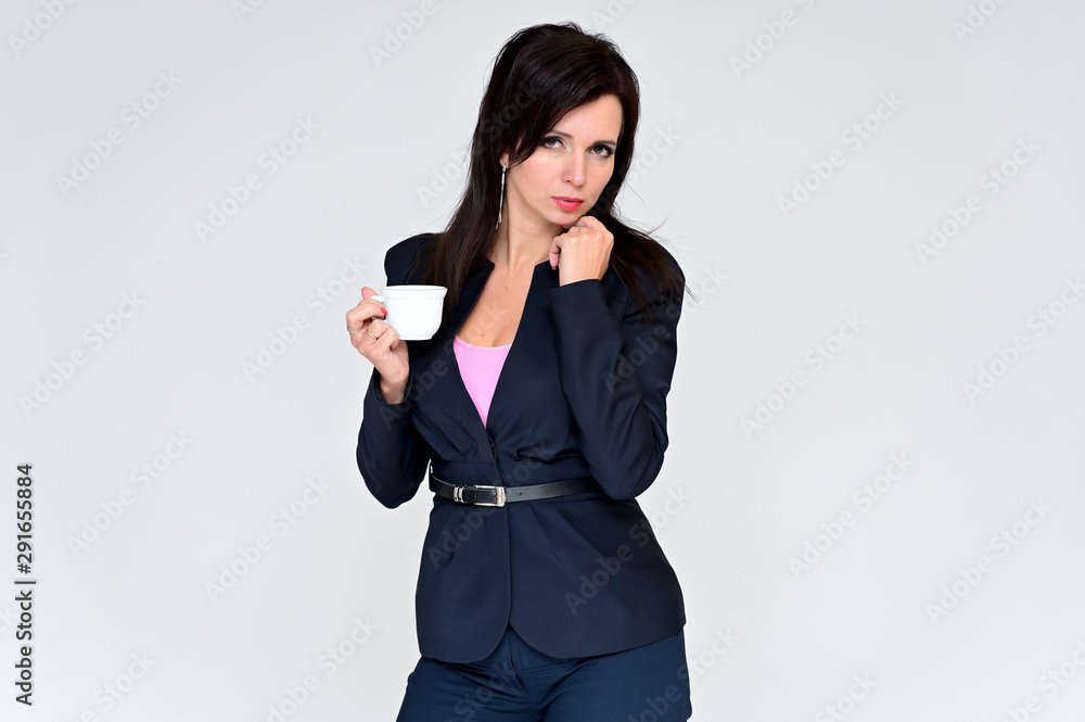 Portrait of a brunette manager woman in a business suit on a white background with a cup of coffee in her hands. Great makeup and beautiful hair. Right in front of the camera in various poses. Portrait of a brunette manager woman in a business suit on a white background with a cup of coffee in her hands. Great makeup and beautiful hair. Right in front of the camera in various poses.