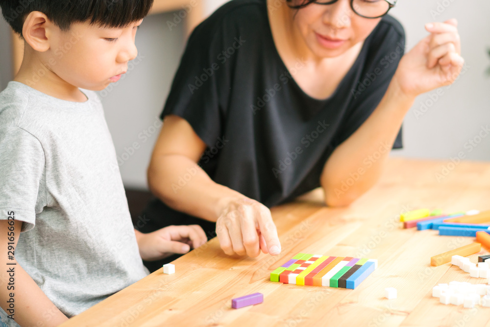 A little asian boy learning about numeracy, adding - subtracting and counting through colorful cuisenaire rods with his mothers. Early math, Cognitive skills, Learning tools, Educational concept. A little asian boy learning about numeracy, adding - subtracting and counting through colorful cuisenaire rods with his mothers. Early math, Cognitive skills, Learning tools, Educational concept.