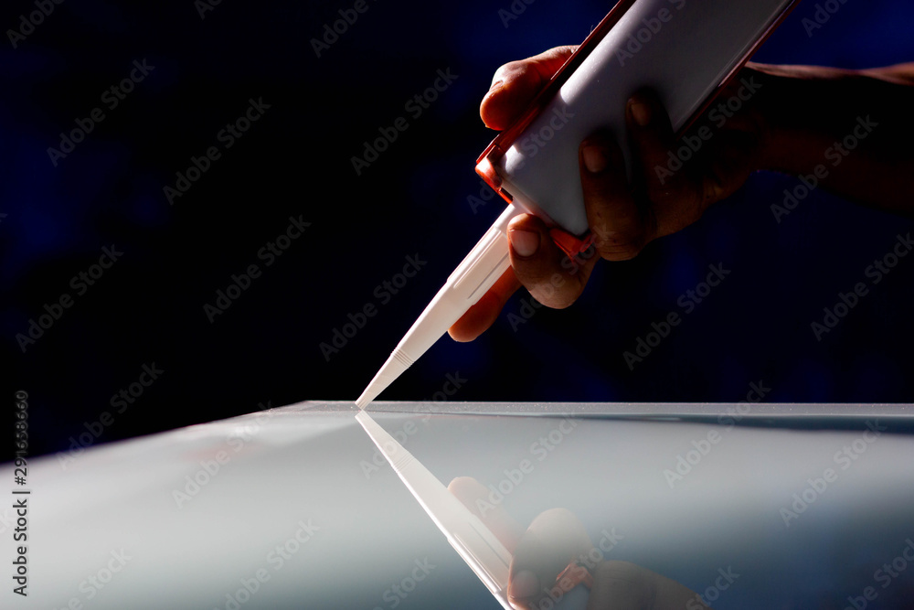 Fototapeta premium The craftsman's hand uses a silicone caulking gun for general and industrial applications.