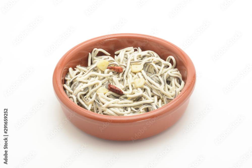 Gulas cocinadas con ajo y guindilla en una cazuela de barro sobre fondo blanco Gulas cocinadas con ajo y guindilla en una cazuela de barro sobre fondo blanco