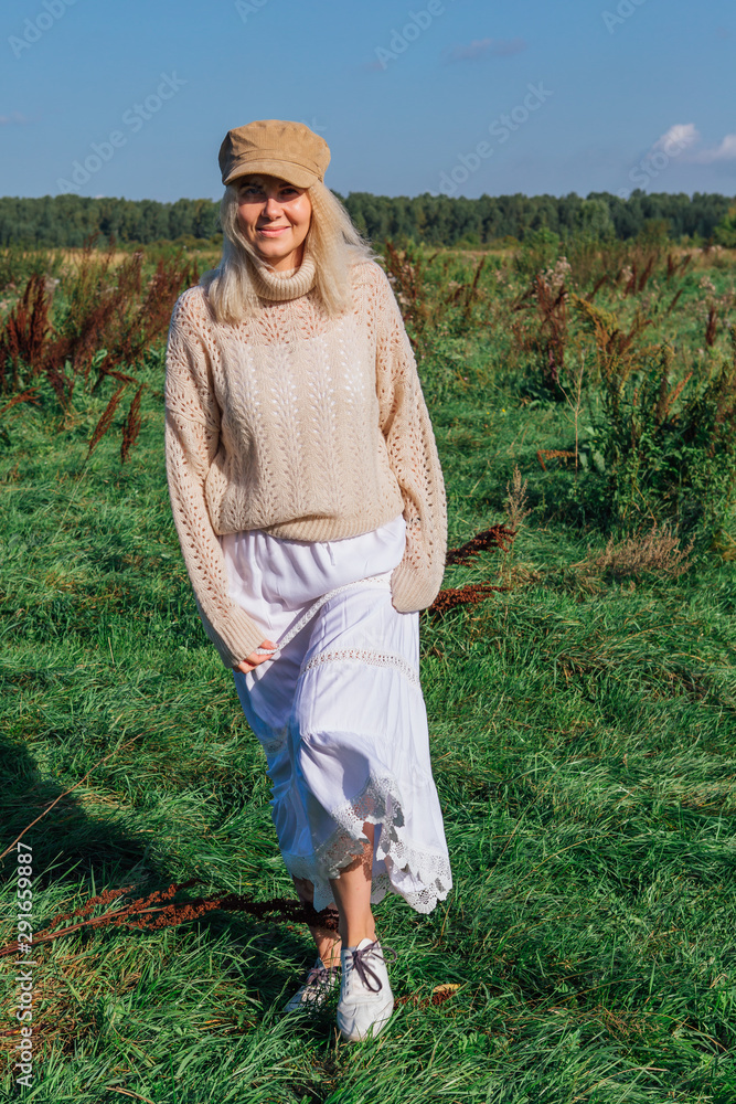 Fototapeta premium Happy beautiful blond woman walking in a green field