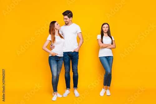 Full size phot of sullen girl looking at sweethearts cuddling wearing white t-shirts denim jeans isolated over yellow background photo