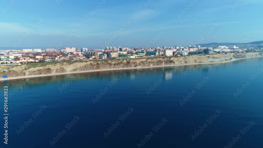 Flying over the sea near the mountains with coastal town, aerial view. Flying over the sea near the mountains with coastal town, aerial view.