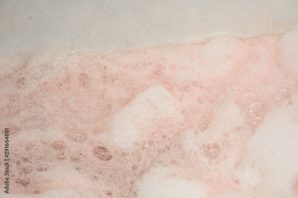Fototapeta premium Soapy foam painted red in the bath is close