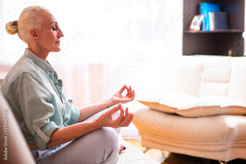 Adults and Seniors Lifestyle Concepts.  Tranquil Caucasian Senior Female During Her Yoga Asana Training On Couch Indoors. © danmorgan12